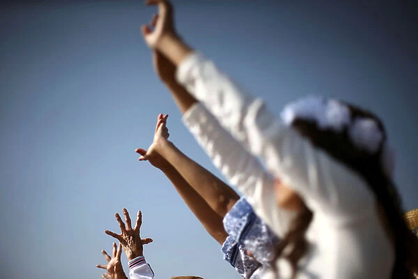 People raise their arms towards the sun to welcome the spring equinox while they are