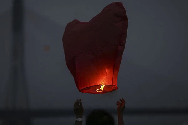 People release paper lanterns during a celebration for the New Year of the Dai minority