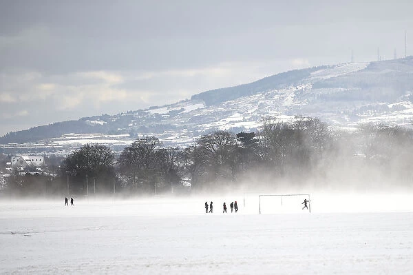 People run on a football field in the snow at the Phoenix Park in Dublin