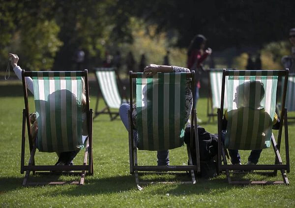 People are silhouetted against their deck chairs as they pose for a selfie photograph