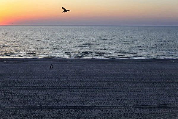 People stroll on the beach at the dawn in the Black Sea resort of Mamaia