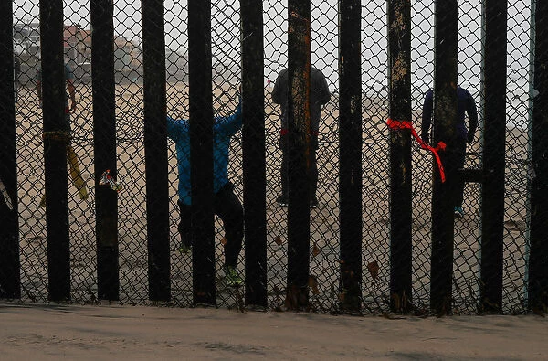 People taking part in morning workout are seen on the Mexico side of the border wall