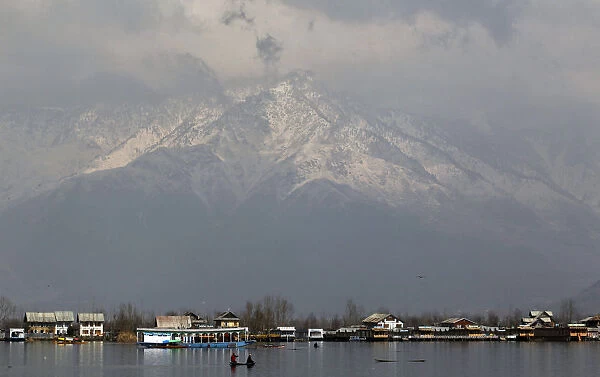 People travel in small boat on waters of Dal Lake on sunny day in Srinagar