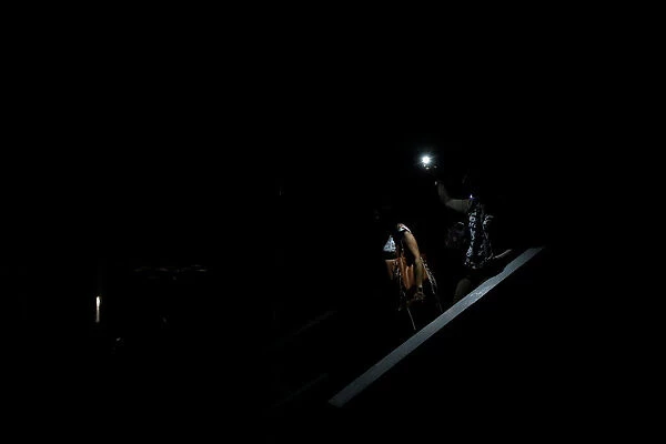 People use light from a phone while they walk on the staircase of a parking garage during