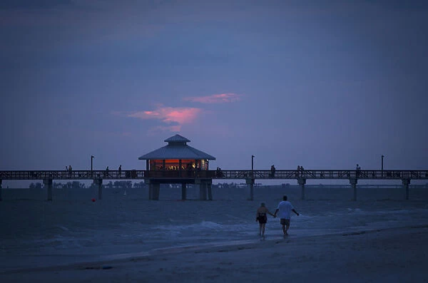 People walk along beach at twilight during the Labour Day long weekend in Ft Myers Beach