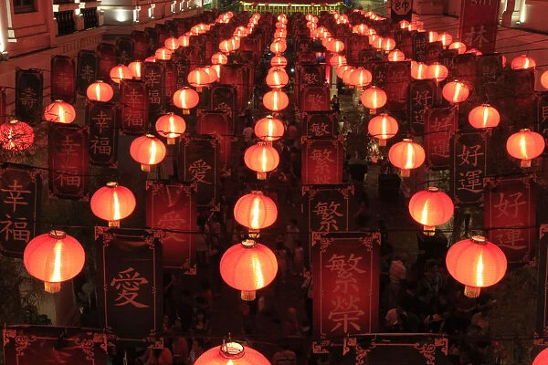 People walk under a Chinese Lantern display during a Chinese New Year eve celebration