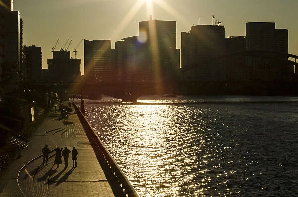 People walk along embankment of Sumida River on sunny winter day during New Year holidays