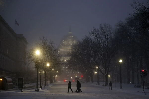 People walk in the falling snow near the U. S. Capitol in Washington