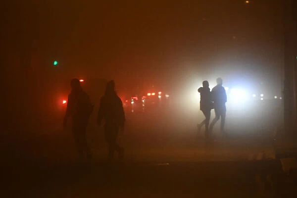 People walk across a road during heavy fog in Dublin