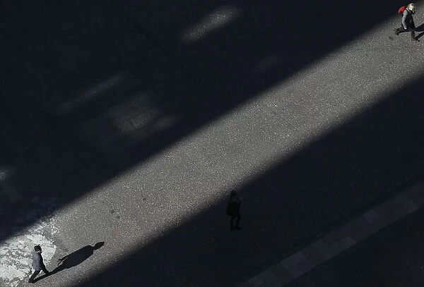 People walk though a shaft of sunlight in London