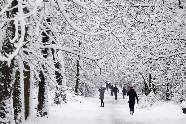 People walk in a snow-covered path in the Bois de Vincennes in Paris, France