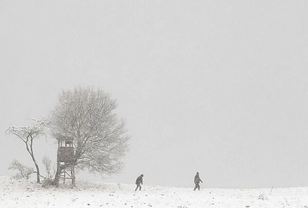 People walk through a snowy landscape near the village of Dorndorf-Steudnitz
