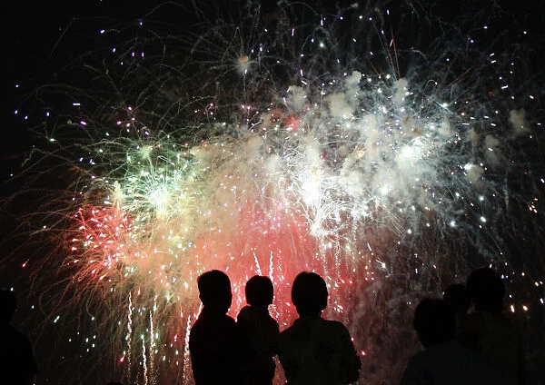 People watch fireworks explode during the Chofu city fireworks festival in Kawasaki