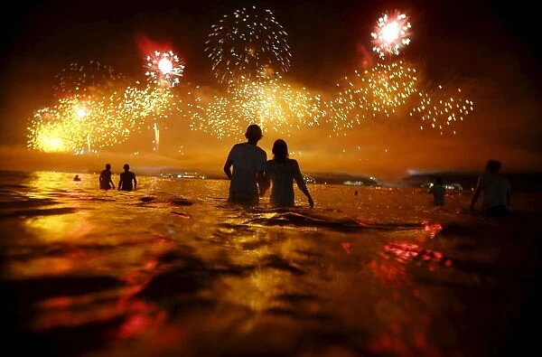 People watch as fireworks explode over Copacabana beach during New Year celebrations