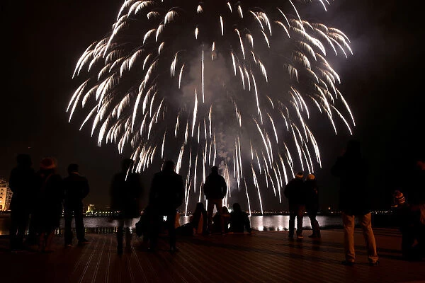 People watch fireworks exploding next to the seaside promenade of the port city of