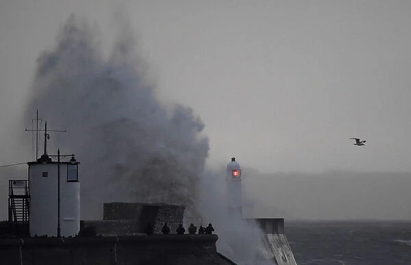 People watch as large waves and high winds associated with Storm Ffion hit the seawall
