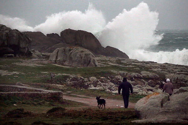 People watch waves breaking on the Brittany coast after storm Eleanor hit Saint-Guenole