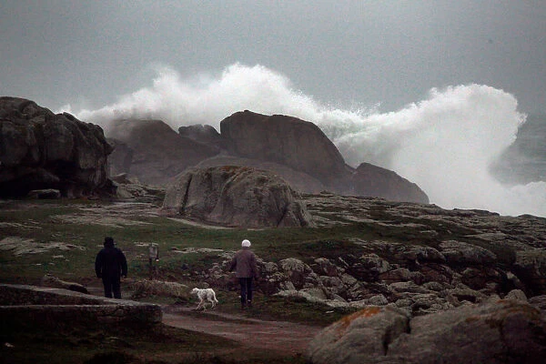 People watch waves breaking on the Brittany coast after storm Eleanor hit Saint-Guenole