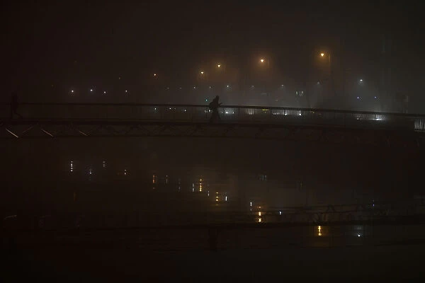 A person crosses a bridge during heavy fog in Dublin