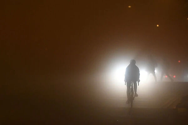A person cycles through heavy fog in Dublin