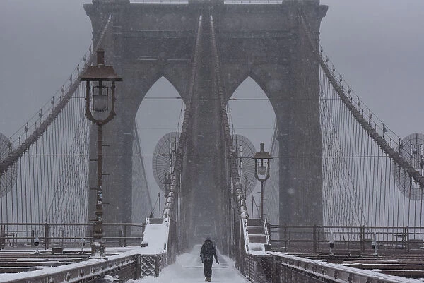 A person walks over the Brooklyn Bridge during winter storm Niko in New York City