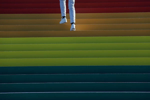 A person walks up a giant LGBTQ Pride Flag installed on the steps of Franklin D