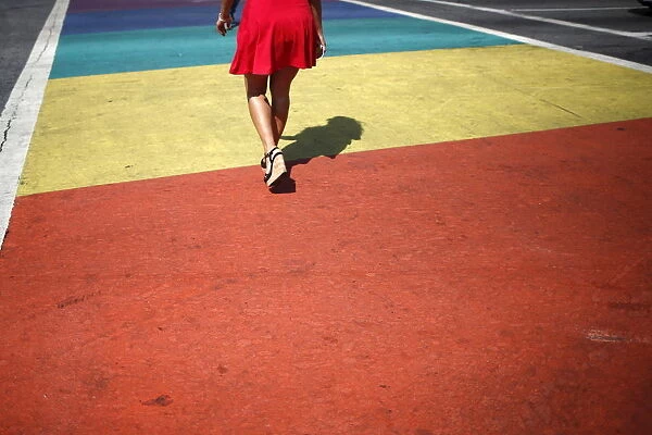 A person walks across a rainbow pedestrian crossing on a road in West Hollywood