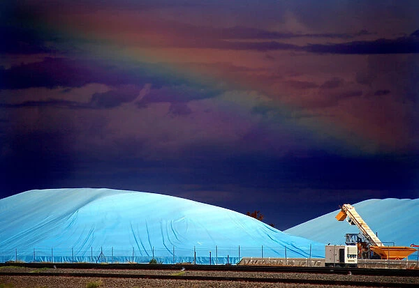Piles of harvested wheat are covered with plastic sheets near the depot for GrainCorp