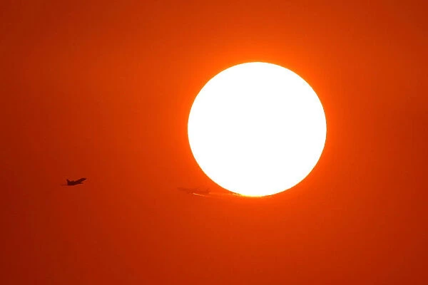 Two planes fly in front of the setting sun in Shanghai