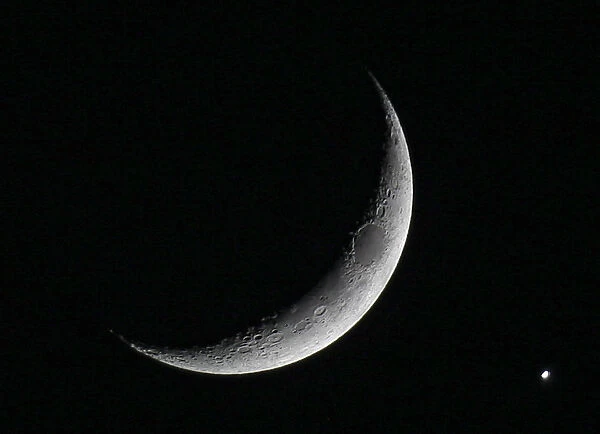The planet Venus is seen after being eclipsed by the crescent moon, as seen from Amman