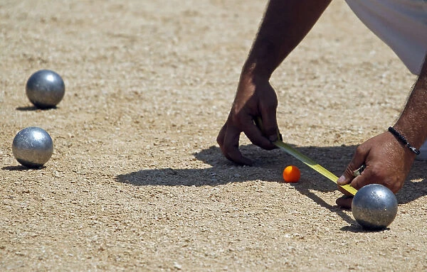 A player measures the distance between petanque bowls during the semi-final of the