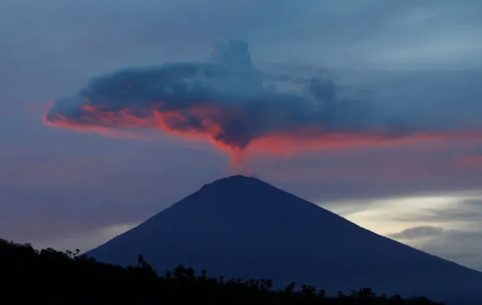 Framed Print : A plume of smoke above Mount Agung volcano is illuminated at sunset as seen from Amed