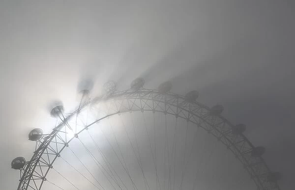 The pods on the London Eye casts shadows against a thick morning fog as the spring