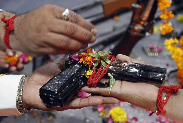 Police officers hold a 9mm pistol as they offer prayers in front of weapons