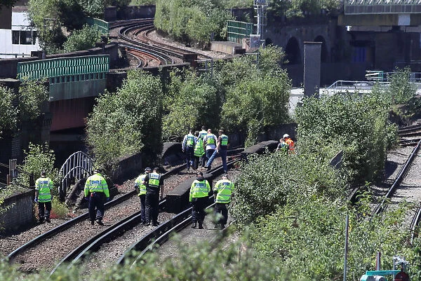 Police officers search near to where three people were found dead on a section railway
