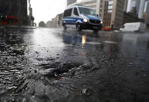 A police vehicle drives on a street during heavy rain in Frankfurt