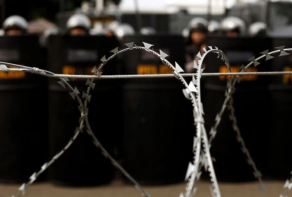 Policemen stand behind barbed wire in front of the presidential palace during a rally in