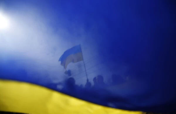 Pro-Ukrainian supporters are seen though a Ukrainian flag as they take part in a rally