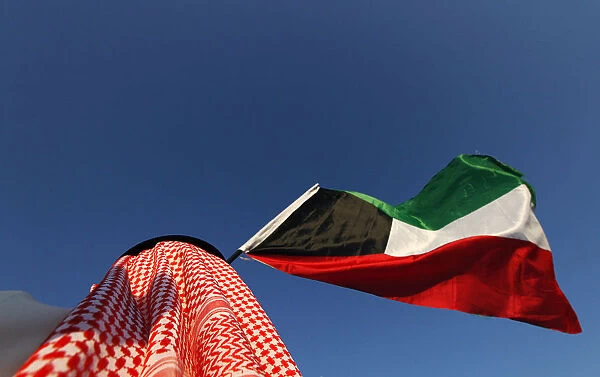 A protester waves Kuwaiti national flag and chants slogans during protest calling for a
