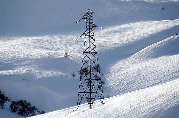 Pylon of high-tension electricity power lines is pictured on snow-covered mountain in