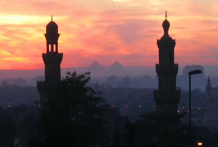 Framed Print : Pyramids of Giza appear between two minarets during a warm winter sunset in Cairo Framed Print : Pyramids of Giza appear between two minarets during a warm winter sunset in Cairo