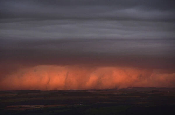 Rain clouds are lit by the setting sun, looking south from Hadrians Wall near Hexham