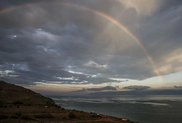 A rainbow is seen over a beach with lifejackets and a boat