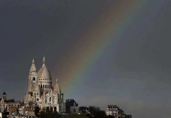 A rainbow is seen against rain clouds above the Sacre Coeur Basilica on Montmartre after