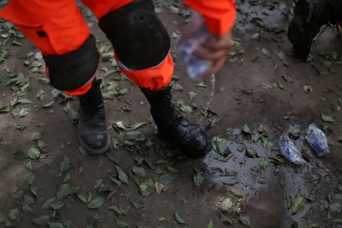 Framed Print : A rescue worker cools off his boots with water near an area affected by the eruption of Framed Print : A rescue worker cools off his boots with water near an area affected by the eruption of