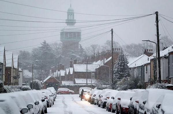 A resident clears snow from a car as the snow falls in Loughborough