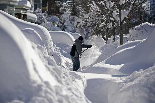 A resident shovels snow away from the entrance to his home in Union City