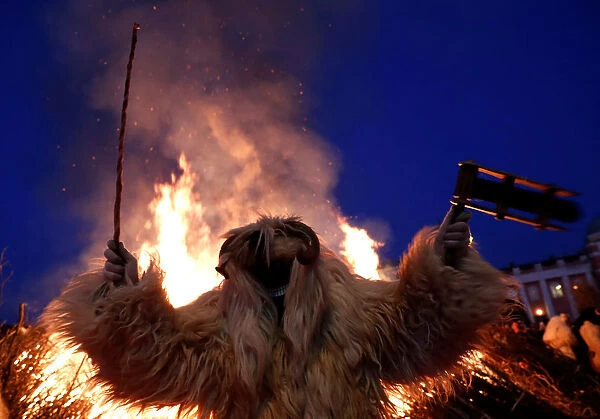 A reveller wearing a mask dances near a bonfire during the traditional Buso Carnival in