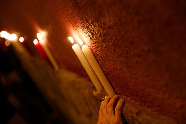 Revellers place candles on a wall after the closing ceremony of the San Fermin festival