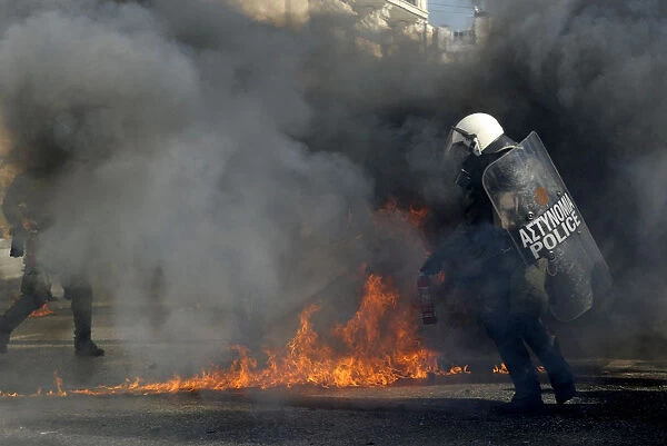 Riot policemen walk by fires caused by petrol bombs during strike in central Athens